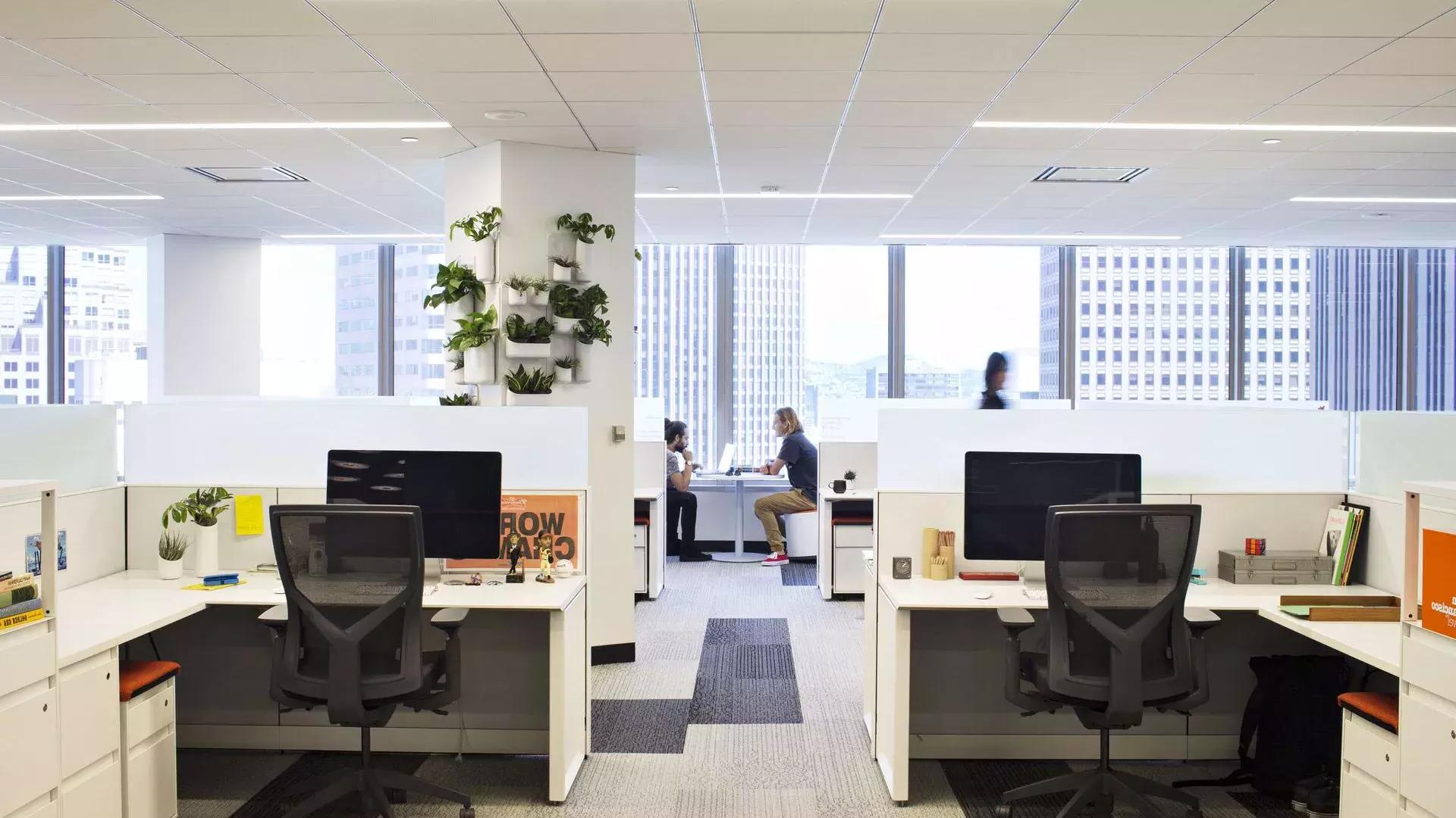 Escena interior de un edificio de oficinas en San Francisco, 两个人在大窗户前的一张桌子上工作.