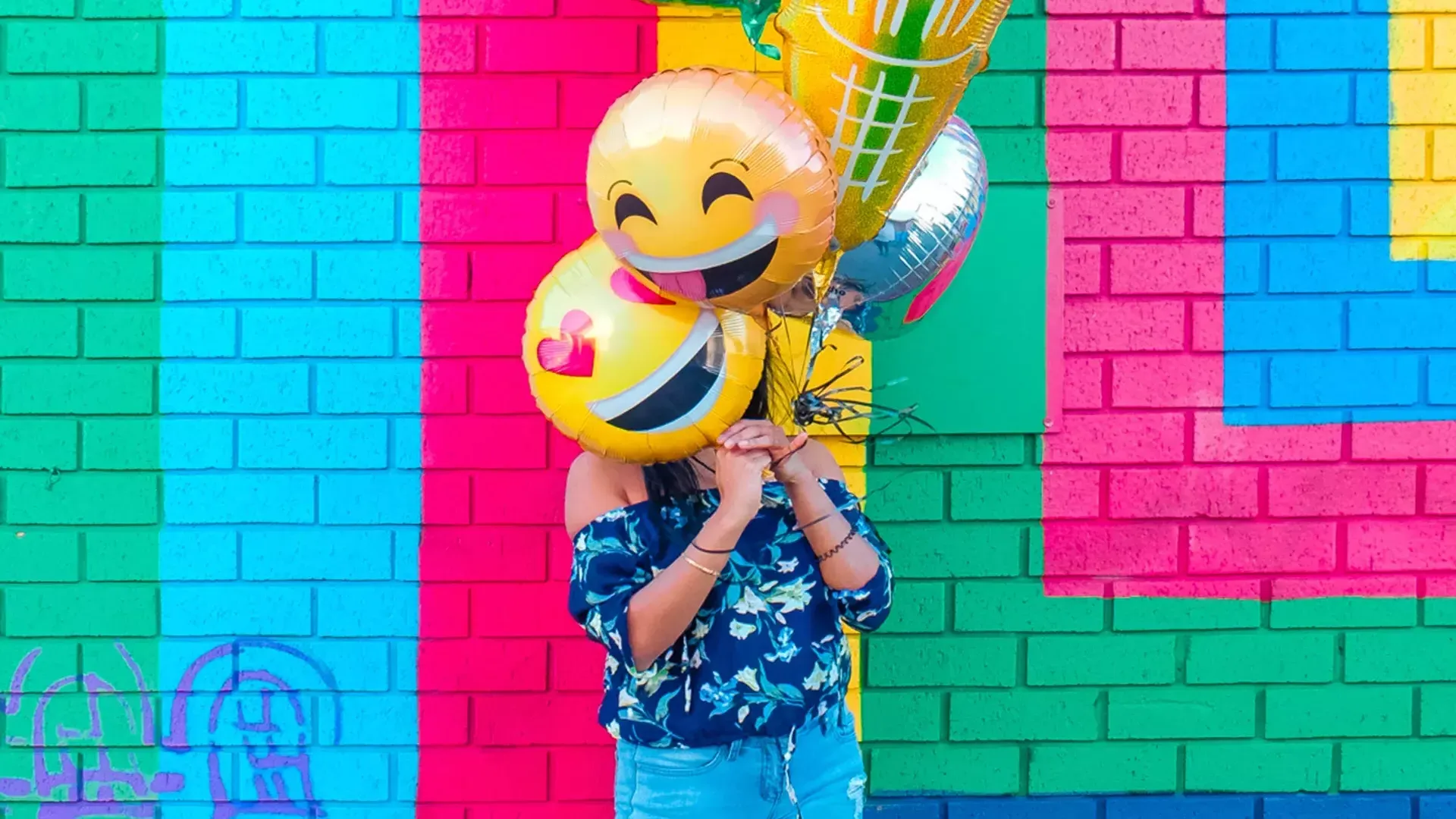 一个女孩在彩色壁画前用气球庆祝生日。。