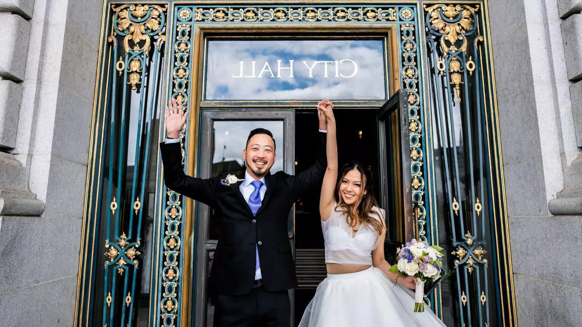 Couple posing in front of city hall after wedding