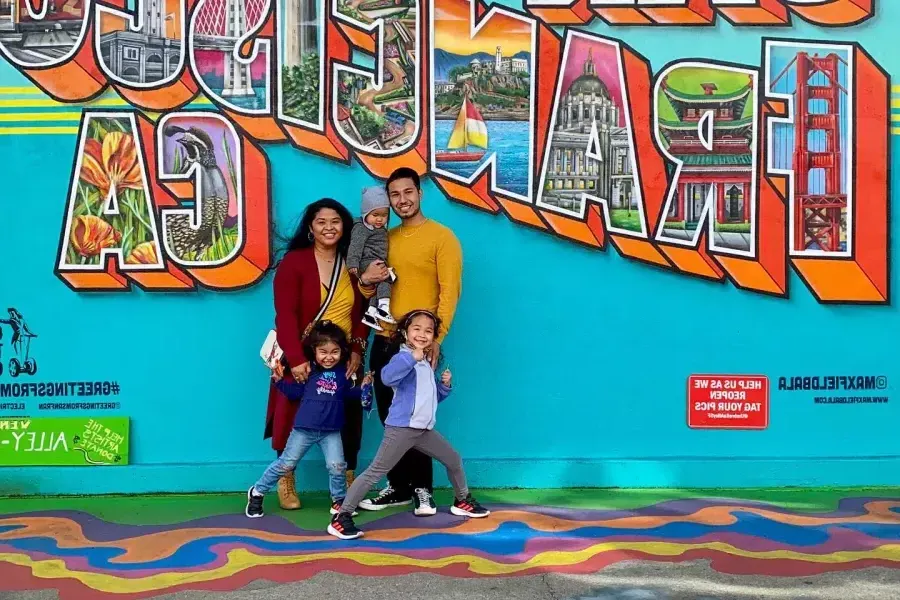Una famiglia in posa per una foto davanti a un murale di San Francisco