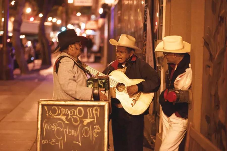 Three Mexican musicians perform on a street in the 任务的区 of San Francisco.