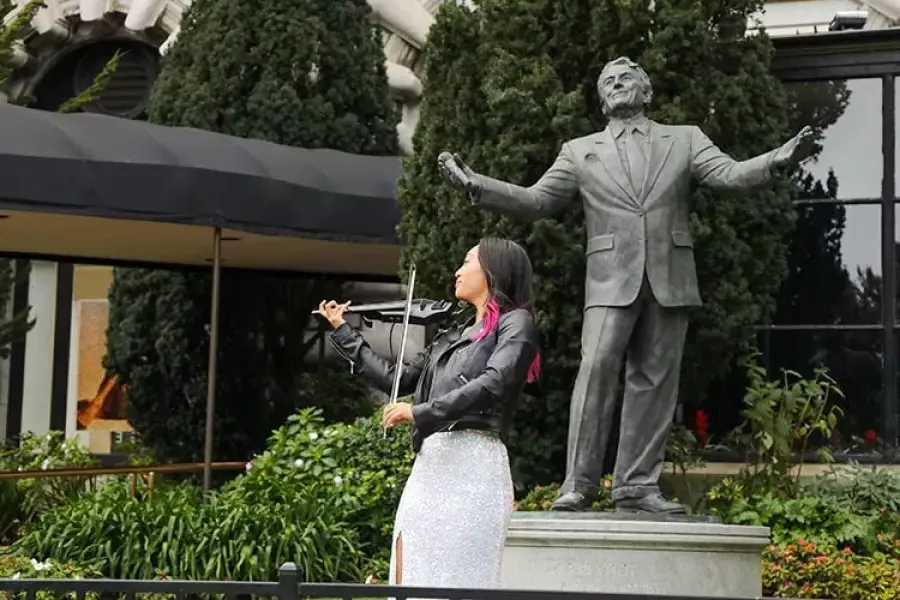 她在费尔蒙特酒店的托尼·班尼特雕像前演奏小提琴。.