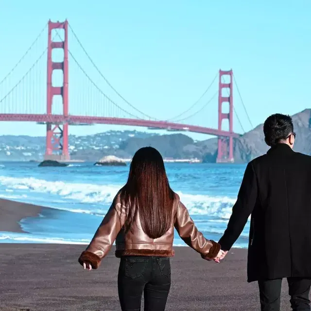 这对夫妇在贝克海滩握手，背景是金门大桥。 